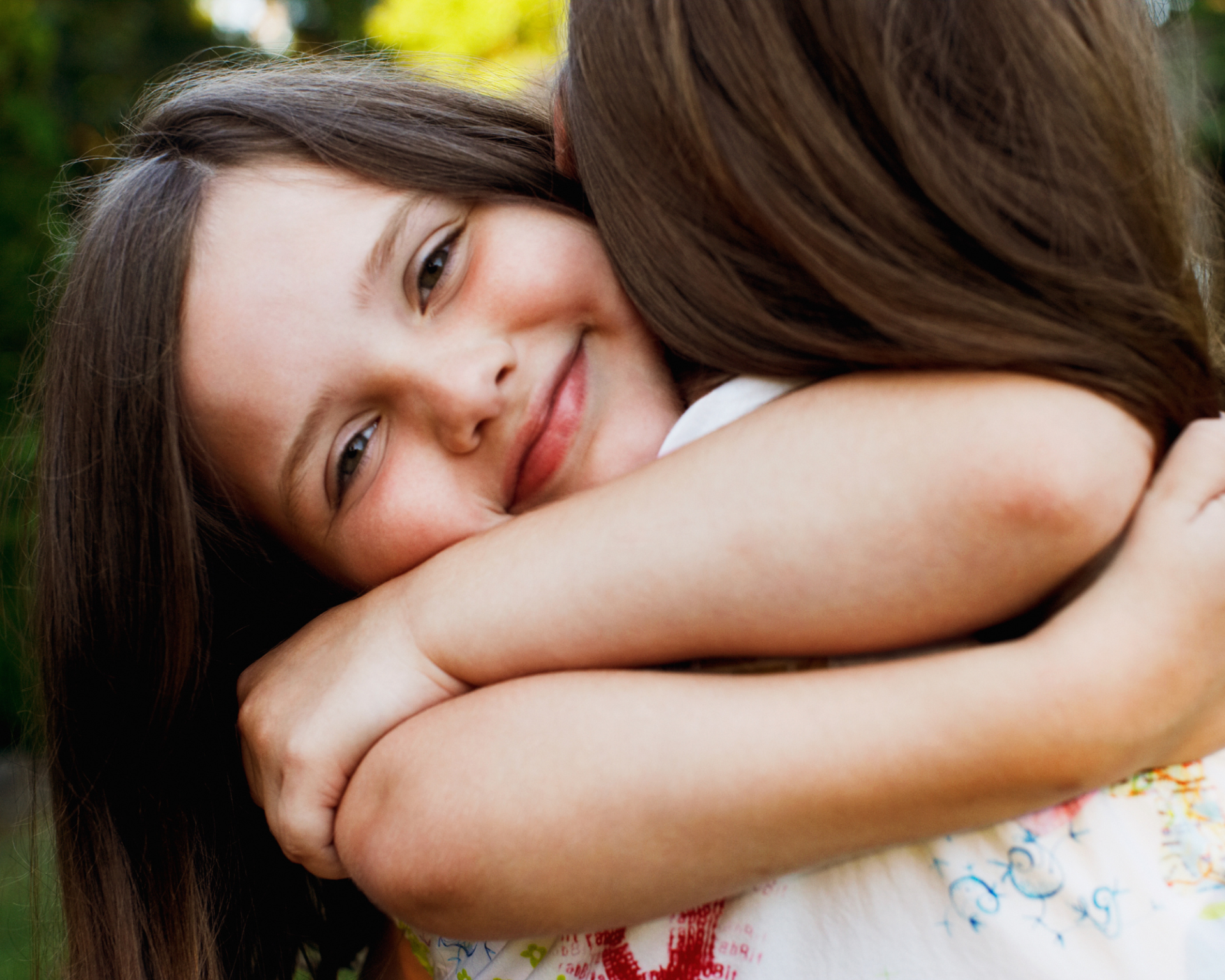 une fille sourit dans les bras de sa maman et fait un câlin d'amour